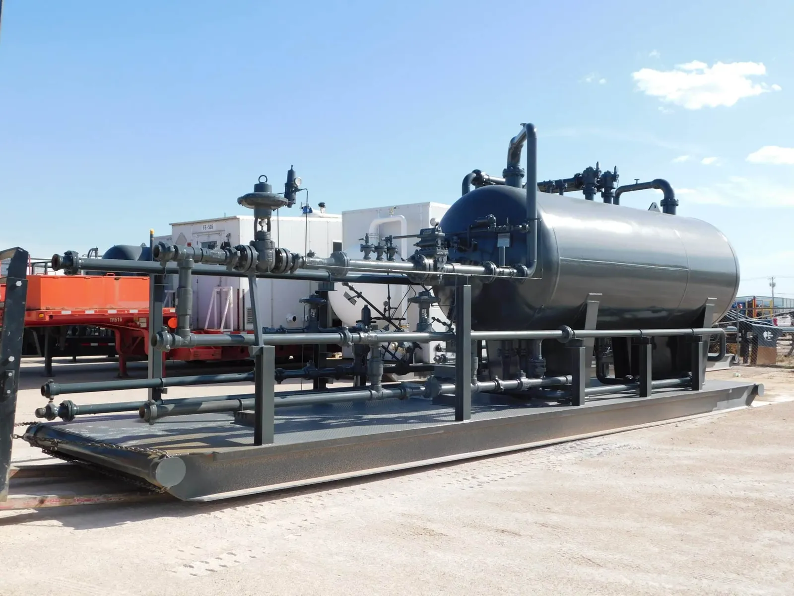 Skid-mounted horizontal separator vessel with its piping manifold in an equipment yard