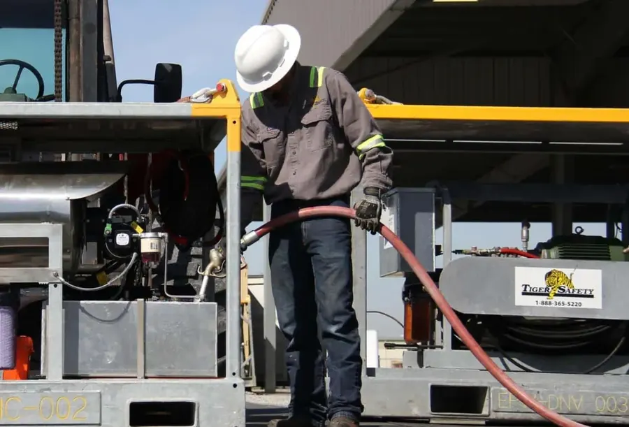 Tiger Safety technician connecting a hose to a rental unit in the equipment yard