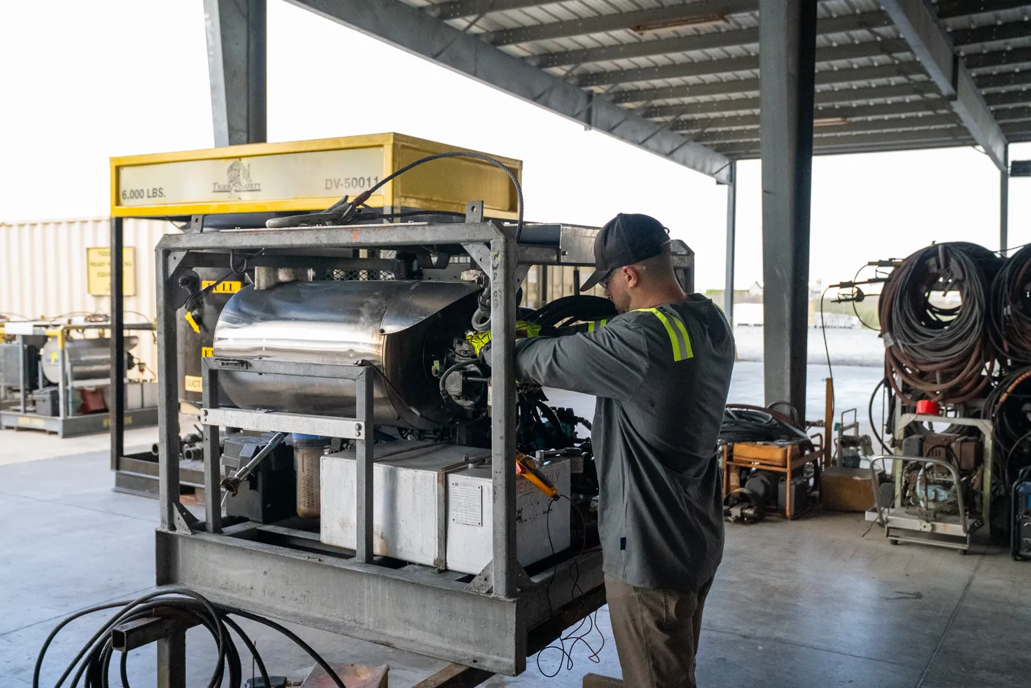 Tiger Safety Rentals technician servicing a skid-mounted unit under the Broussard, Louisiana shop canopy, with hose reels nearby